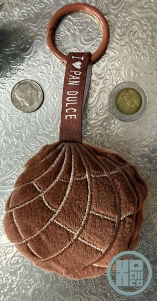 Plush pan dulce concha chocolate key chain with ribbon and carabiner clip.